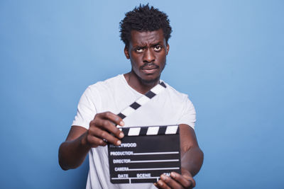 Portrait of young man using mobile phone against blue background