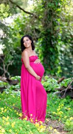 Portrait of woman standing against pink plants
