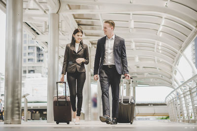 Business people with luggage talking while walking on street