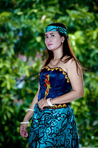 Young woman looking away while standing against plants