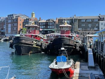 Boats moored at harbor against clear sky