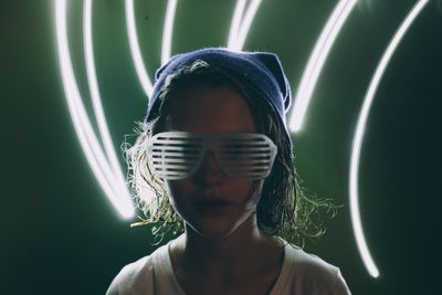 Portrait of girl wearing novelty glasses with light painting against green background