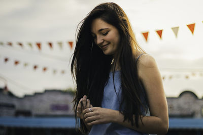 Smiling young woman standing against sky during sunset