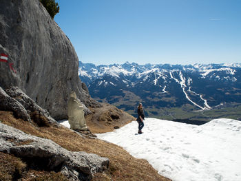 Rear view of man climbing on mountain against sky