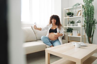 Young woman using mobile phone while sitting on sofa at home