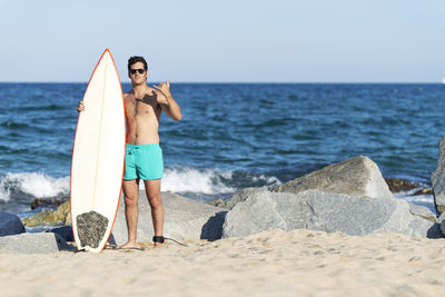 Rear view of man standing at beach against clear sky