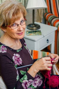 Portrait of woman holding eyeglasses at home