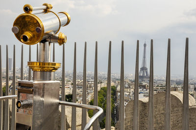 Hand-held telescope against eiffel tower in city