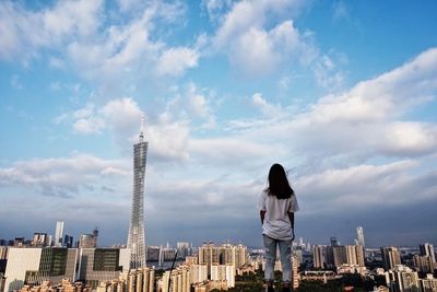 Woman standing by cityscape against sky