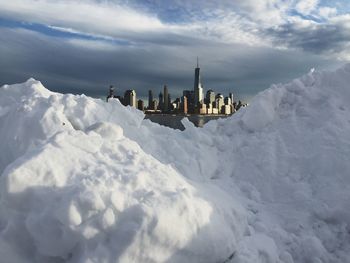 One world trade center amidst buildings in front of snow during sunny day