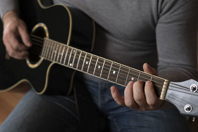 Midsection of man playing guitar