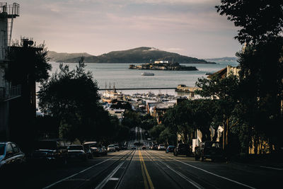 Road leading towards sea against sky in city