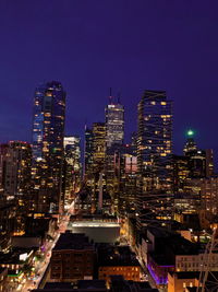 Illuminated buildings in city against clear sky at night