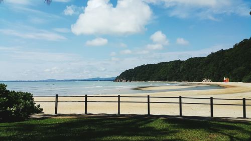 Scenic view of beach by mountain against sky