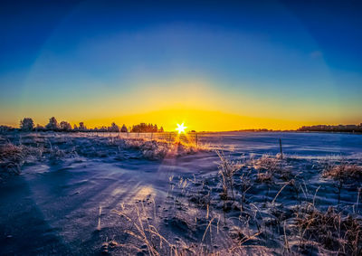 Scenic view of snow covered field against sky during sunset