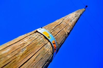 Low angle view of old bamboo against clear blue sky