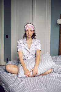 Woman in pajamas and with a sleep mask on the bed in the bedroom