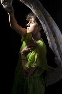 Low angle view of young woman standing against black background