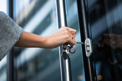 Cropped hand of woman opening door with keys