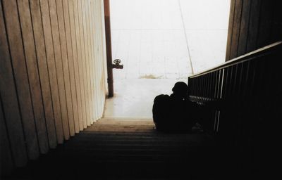 Rear view of silhouette man sitting on staircase in building