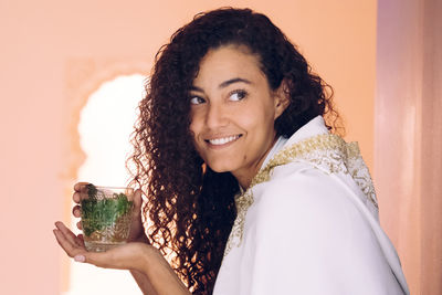 Smiling woman looking away while holding drink