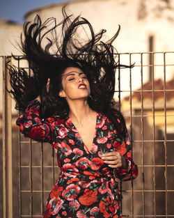 Beautiful young woman smiling while standing against fence