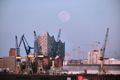 Cranes and buildings against sky