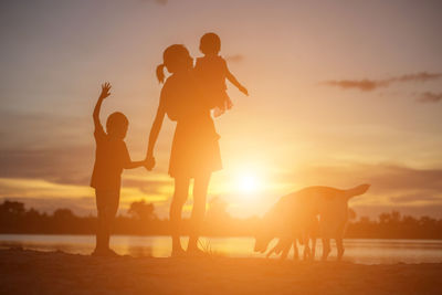 Silhouette people on land against sky during sunset