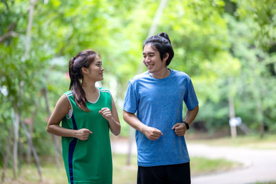 Smiling young woman standing against trees