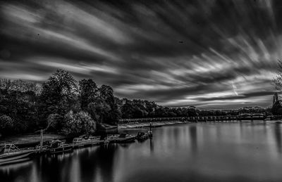 Scenic view of river by illuminated city against sky at night