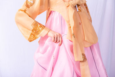 Close-up of woman with pink umbrella standing against gray background