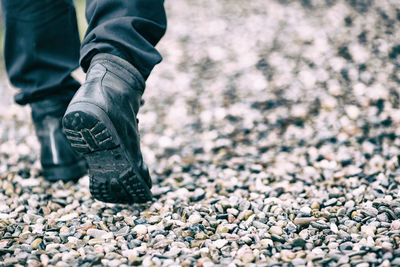 Low section of man walking on pebbles