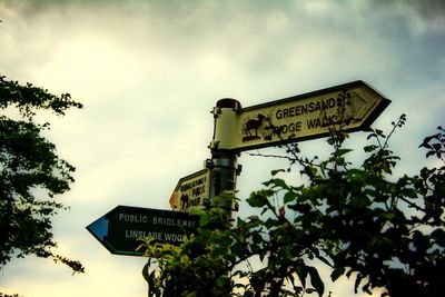 Low angle view of sign board against cloudy sky