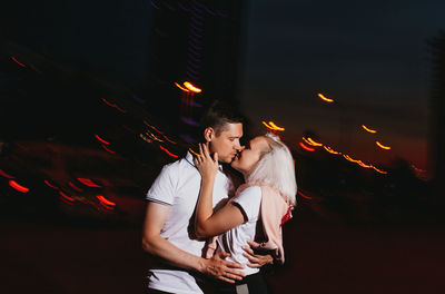 Couple kissing while standing outdoors at night