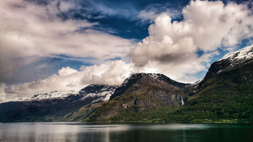 Scenic view of mountains and lake against cloudy sky