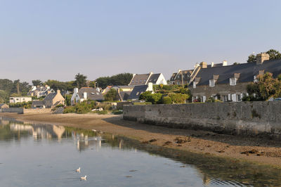 Buildings by lake against clear sky