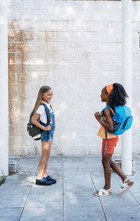 Laughing african american girl walking with friend on street in bright day