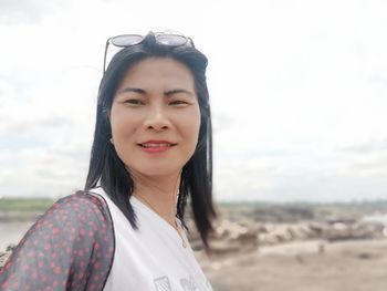 Portrait of smiling woman on beach against sky