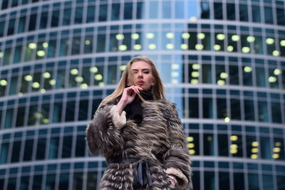 Portrait of young woman against building