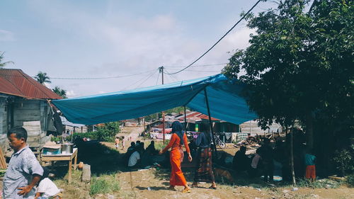 People at market stall against sky