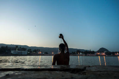 Rear view of man bathing in river against sky