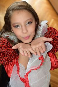 High angle portrait of girl in costume blowing kiss at home