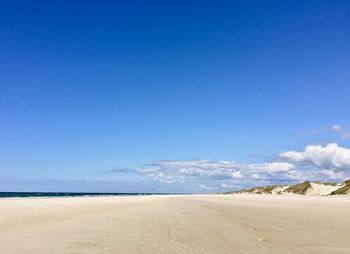 Scenic view of beach against blue sky