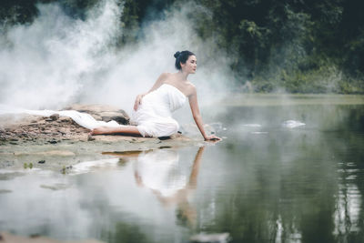 Side view of man sitting in lake