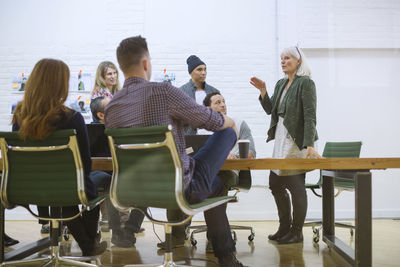 Business people looking at businesswoman explaining in meeting at board room