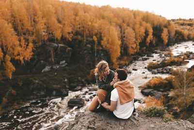 Rear view of couple sitting on rock