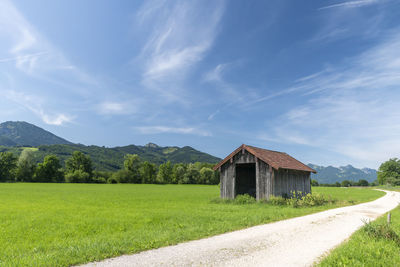 Bavarian meadow landscape with wooden hut, light path, blue sky and copy space