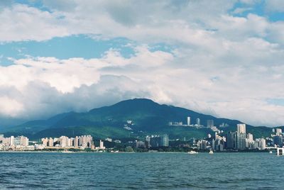 Sea by city buildings against sky