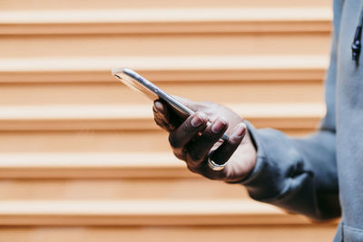 Young man with smart phone by brown corrugated wall