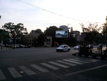 Cars on city street against sky